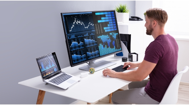 Man working on a large screen monitor that is displaying graph, charts, and tables