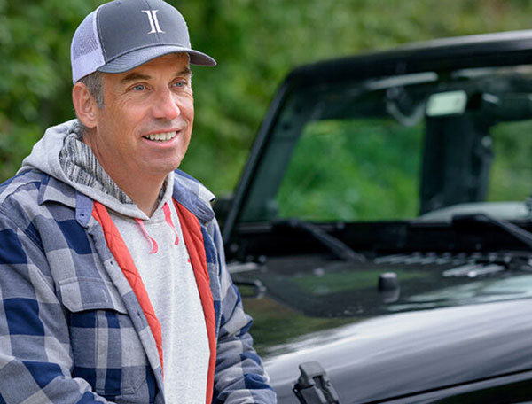 Man standing by a car looking past the camera