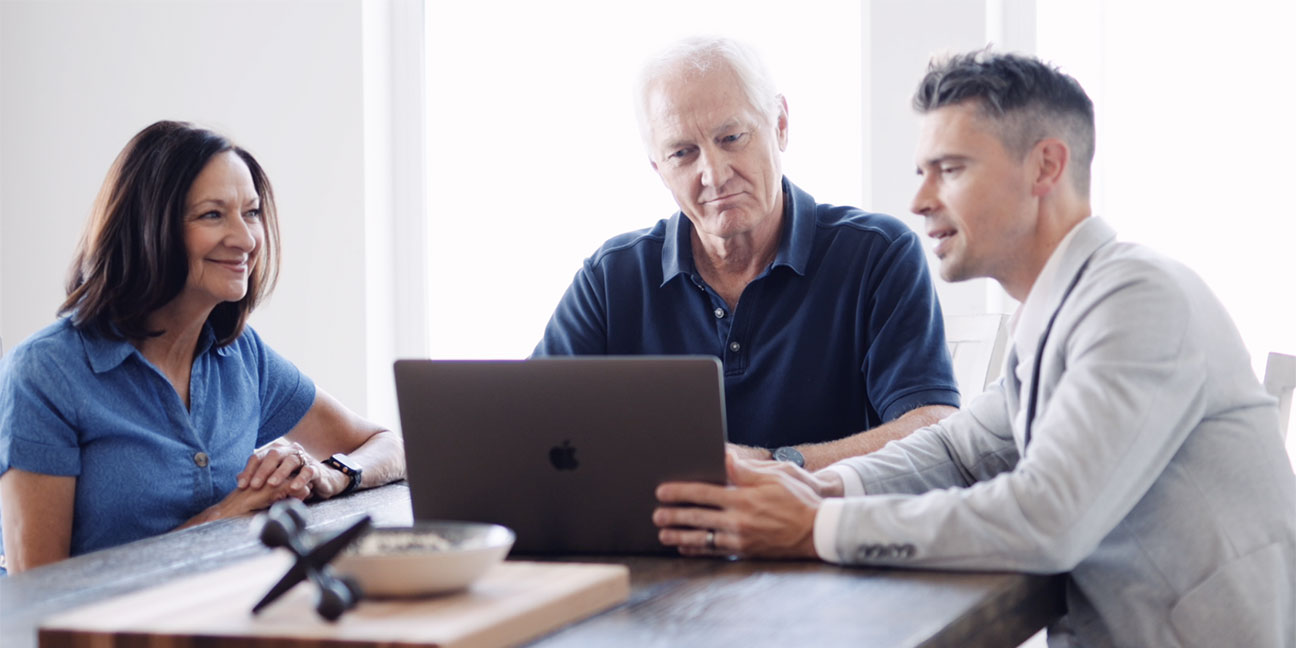 Man showing older couple a laptop