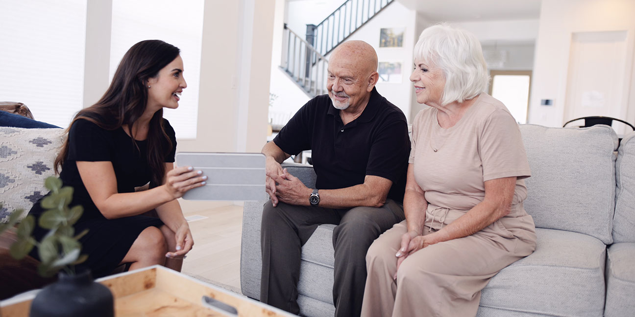 A woman talking to a couple on a couch