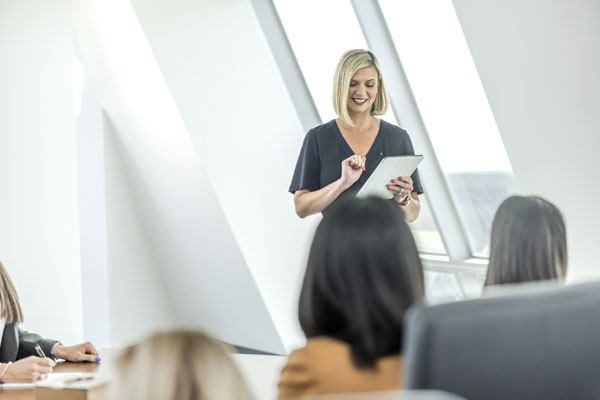 Woman looking at an iPad in front of a crowd